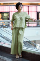 woman wearing light green loose fit co-ord set with short sleeves and wide-leg pants standing indoors