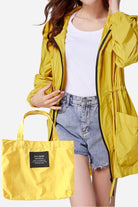 Travel ready outdoor raincoat windbreaker in yellow with matching packable bag, waterproof and lightweight design for travel and outdoor use.