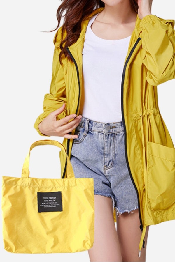 Travel ready outdoor raincoat windbreaker in yellow with matching packable bag, waterproof and lightweight design for travel and outdoor use.