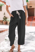 Woman wearing black relaxed fit straight pants with drawstring waist and white t-shirt outdoors