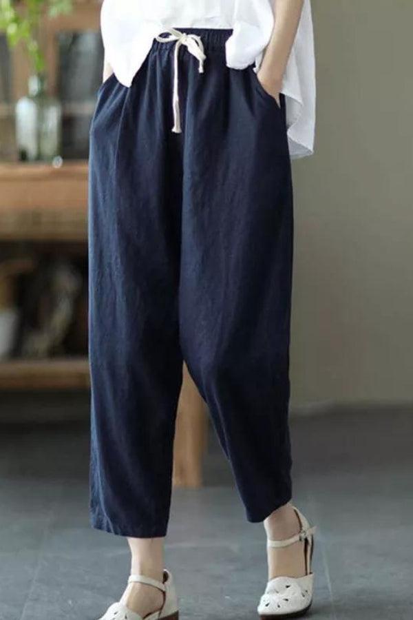 Woman wearing navy blue relaxed fit straight pants with drawstring waist and white top