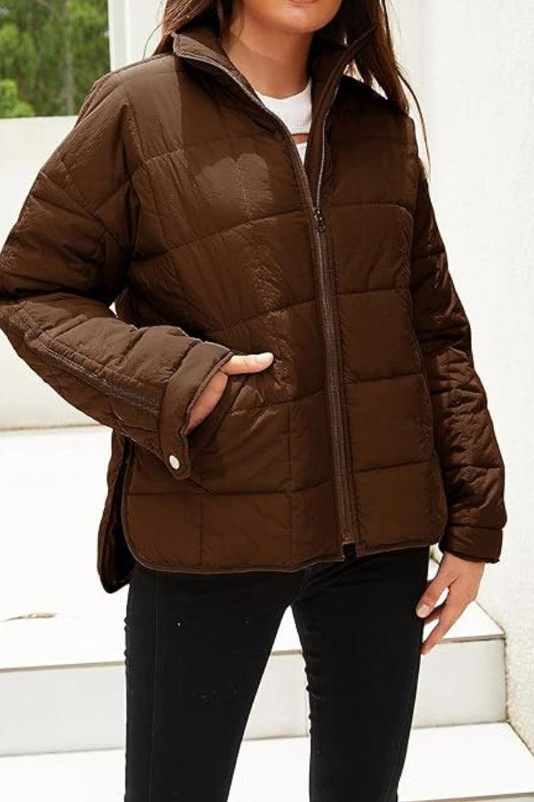 Woman wearing brown lightweight puffer travel jacket with front zipper and side pockets outdoors