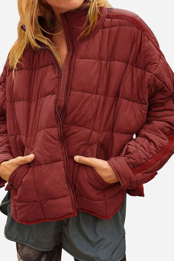 Woman wearing a maroon lightweight puffer travel jacket with quilted design and front pockets
