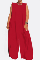 Red sleeveless wide-leg jumpsuit with sharp shoulders and long flowing legs, styled with a chunky necklace and bracelet.