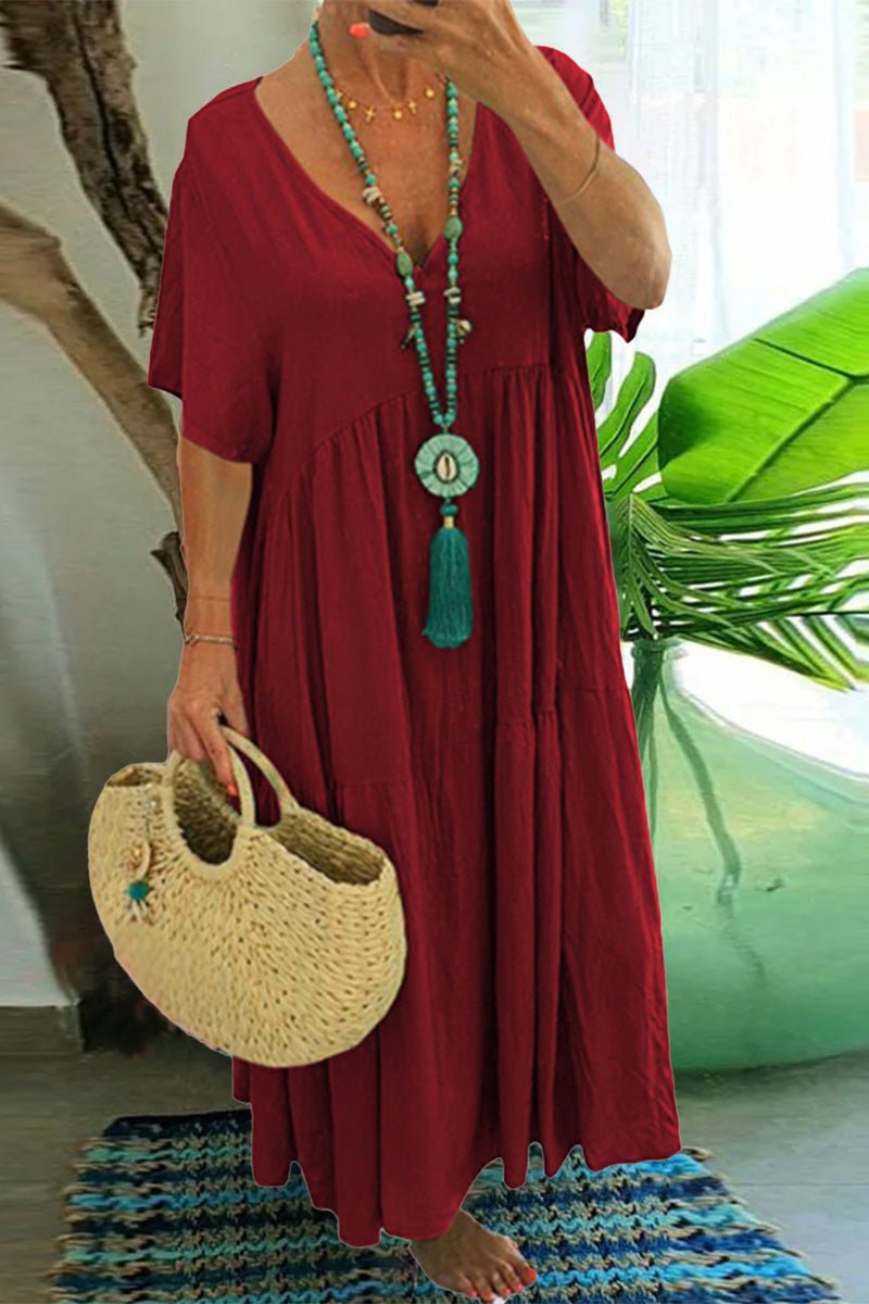 Red V-neck two-tiered maxi swing dress with loose sleeves and flowy hem, accessorized with turquoise necklace and straw handbag.