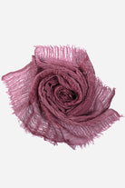 Lightweight linen scarf in dusty rose with frayed edges, folded in a rose shape