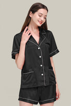 Woman wearing black Mulberry silk buttoned short set pajamas with white piping