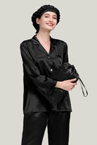 Black Mulberry Silk Pajama Set with matching sleep cap shown on model holding a silk pouch