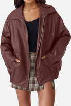 Oversized faux leather motorcycle jacket in brown with zipper and pockets, styled with plaid skirt and black top