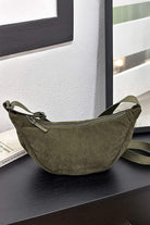 Olive green corduroy shoulder bag with adjustable strap and zip closure on black surface