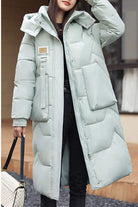 Woman wearing light grey FrostLine Long Coat winter travel coat with hood and large front pockets