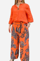 Woman wearing orange Vibrant Fusion Two-Piece Set with printed pants and solid top