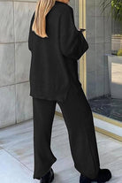 Woman wearing black Travel-Ease Two-Piece Set from behind, standing near glass door