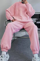 Pink comfy chic tracksuit with relaxed fit, long sleeves, and elastic cuffs, paired with white sneakers.