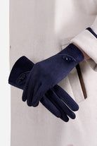 Navy blue SmartTouch suede gloves with touchscreen fingertips and button details on wrist worn with beige coat