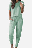 Woman wearing ultra-soft two-piece loungewear set in green with batwing sleeves and jogger pants with pockets.