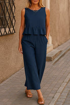 Woman wearing navy blue sleeveless linen-like feel set with peplum top and wide-leg pants walking outdoors