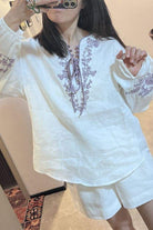 Woman wearing 100% linen two-piece set with floral embroidery in white breathable fabric