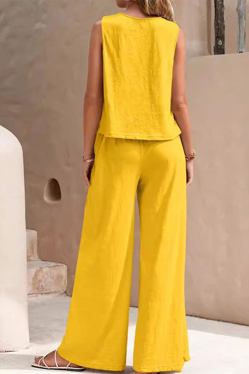 Woman wearing yellow sleeveless wide leg pants set from the back in a minimal neutral setting
