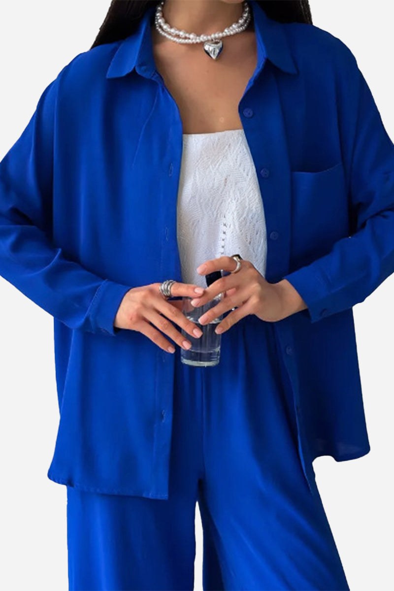 Woman wearing relaxed fit wide-leg two-piece set in vibrant blue with white inner top, holding a glass of water