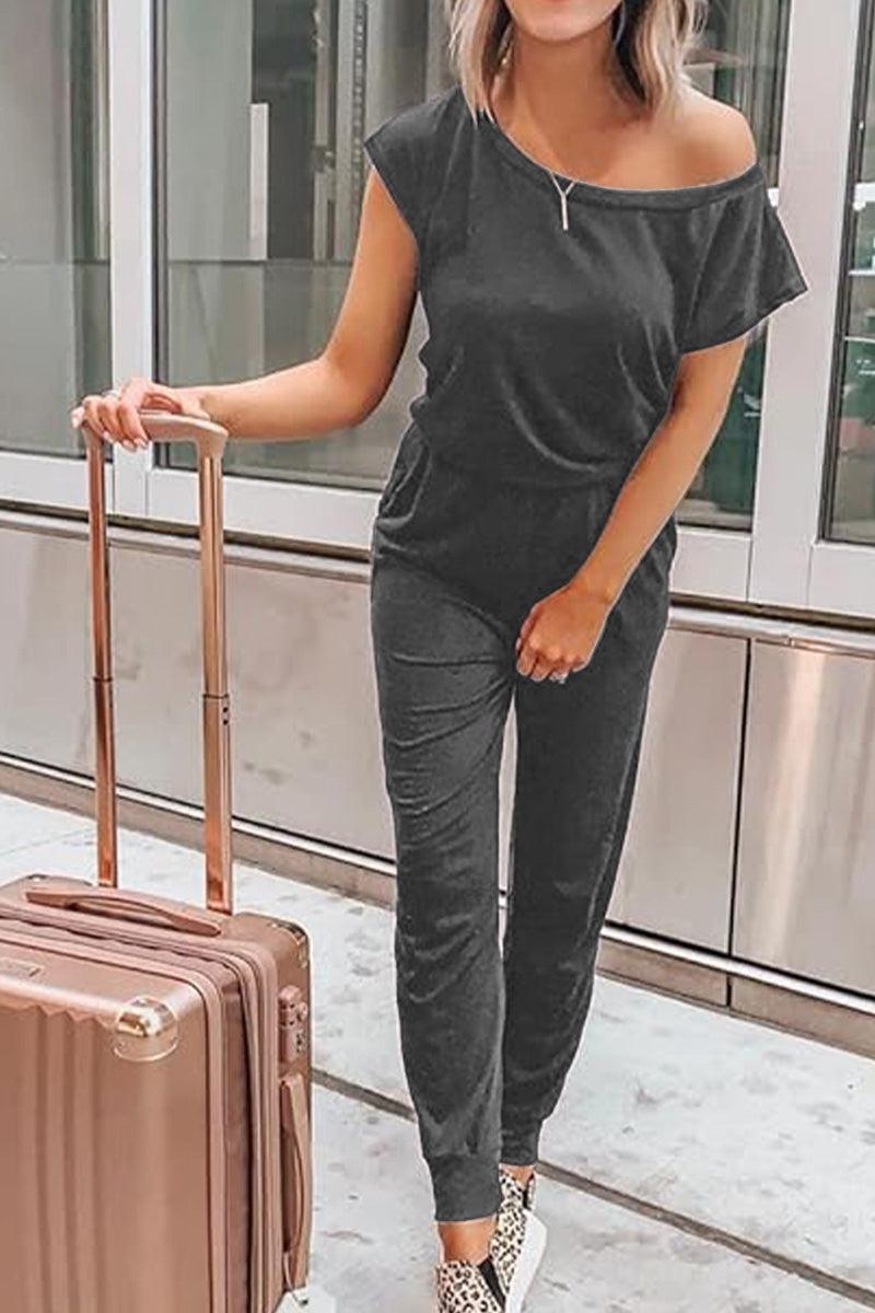 Woman wearing Moonlit Rome Off-Shoulder jumpsuit with suitcase in modern indoor setting