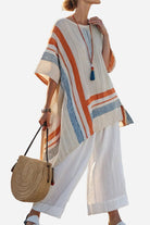 Woman wearing Coastal Comfort Linen two-piece set with wide-leg pants and striped linen tunic, holding round straw bag.