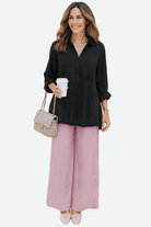 woman wearing oversized linen leaved-in set with black linen-blend shirt and pink palazzo pants holding coffee cup