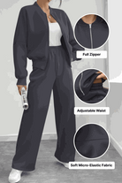 The Voyager Zip Set in black with full zipper jacket and adjustable waist wide-leg joggers in soft micro-elastic fabric, styled with white sneakers.