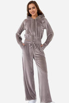 Woman wearing grey velour tracksuit with cropped hoodie and high-waist pants