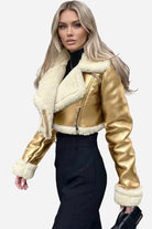 woman wearing cropped faux leather sherpa jacket with cream sherpa lining and gold faux leather outer