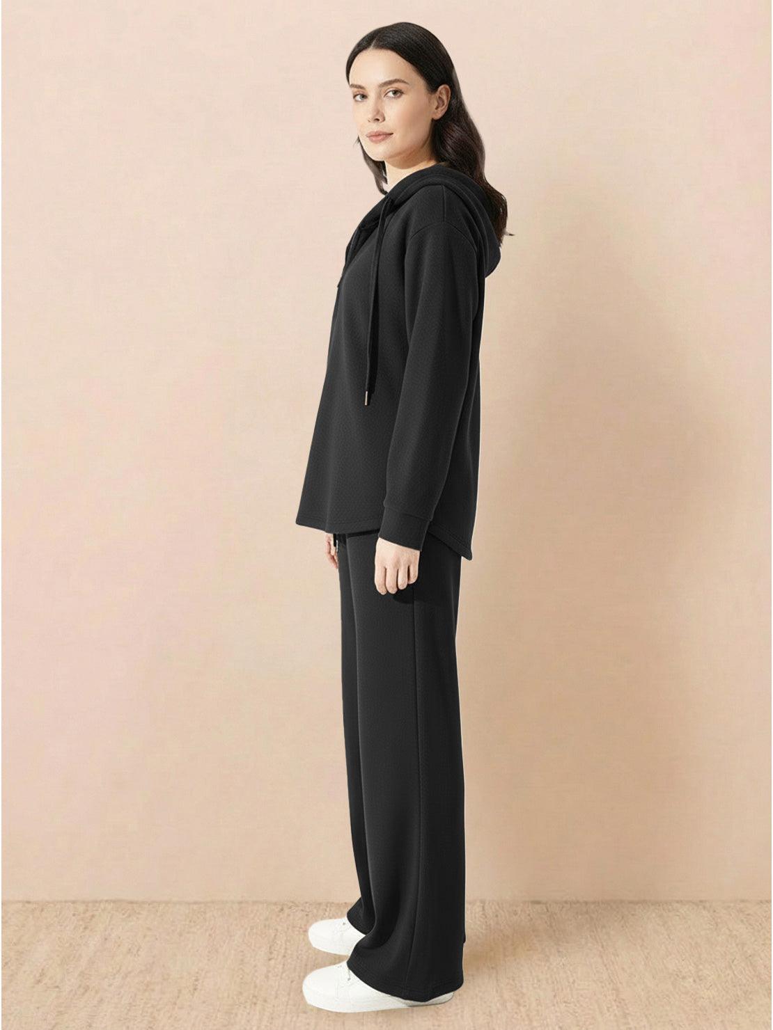 Woman wearing black lyocell-blend hooded set with wide-leg pants and hooded top in side view