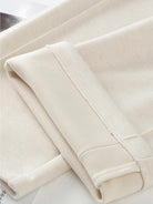 Close-up of beige thermal wool blend trousers fabric with folded hems showing soft texture and stitching details