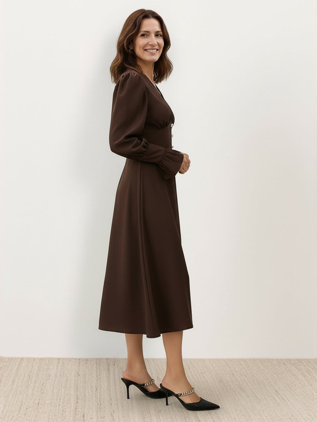 Woman wearing slimming V-neck midi dress with button-front and ruffle cuffs, standing outdoors