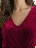 Woman wearing deep V-neck velvet suit with long sleeves and wide-leg pants standing indoors