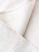 Cotton-linen sleeveless top with round neckline and button closure, relaxed A-line silhouette, hip-length design, natural fabric blend.