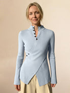 Woman wearing slim fit asymmetric wrap ribbed knit top with diagonal button closure and flared cuffs