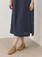 Woman wearing a 100% linen pocket midi dress with short sleeves and side slits