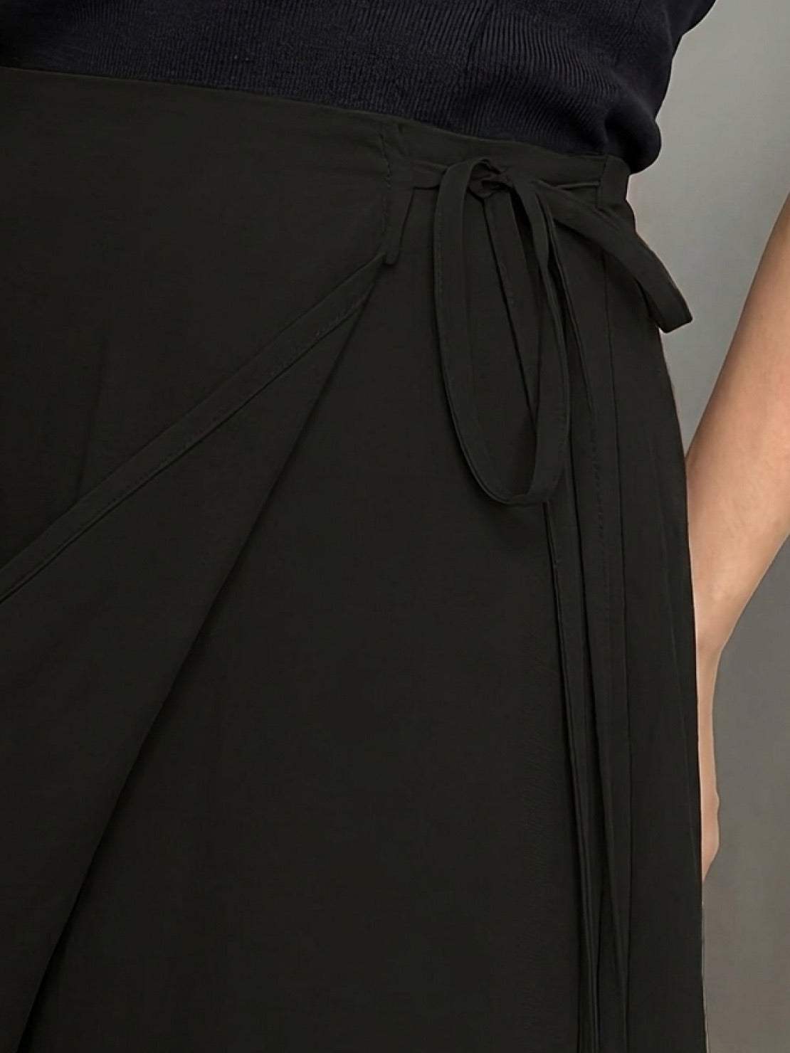 woman wearing asymmetrical wrap maxi skirt with side tie and flowing asymmetric hem