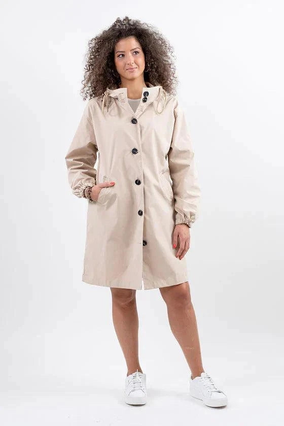 Beige oversized water-resistant windbreaker rain jacket with hood and button closure worn by woman
