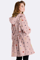 Water resistant oversized windbreaker rain jacket with hood, pink with multicolor pattern, worn by woman facing sideways