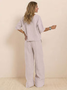 Woman wearing a beige short-sleeved pullover and wide trouser matching set standing against a plain background