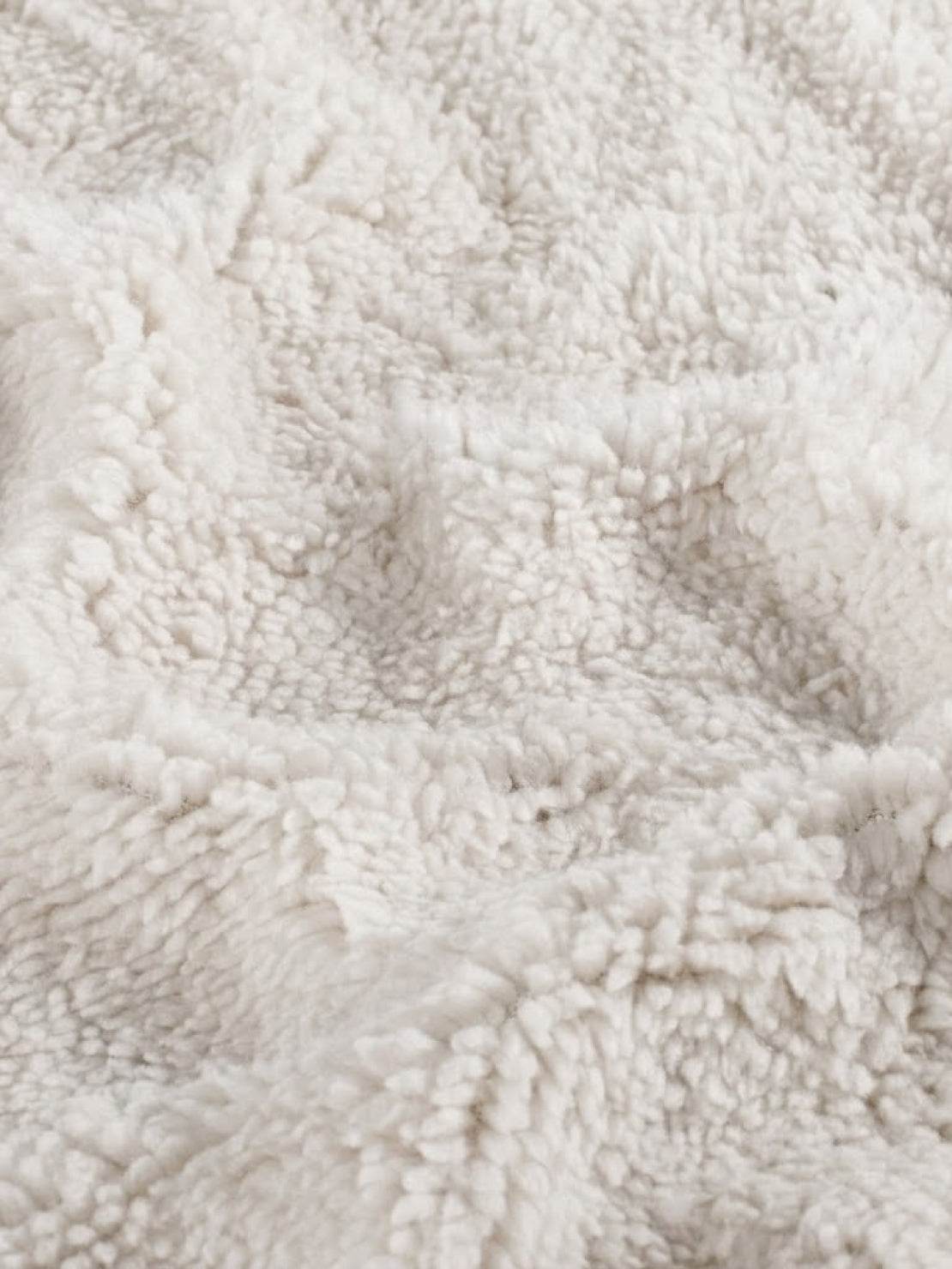 Close-up of soft beige sherpa fabric texture for everyday wear oversized coat lining