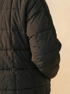 Black lightweight puffer travel jacket with quilted design and soft fabric texture.