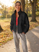 Woman wearing black lightweight puffer travel jacket outdoors on a fall day