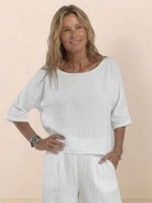 Woman wearing white short-sleeved pullover and wide trouser matching set in breathable cotton fabric with relaxed fit and deep pockets.