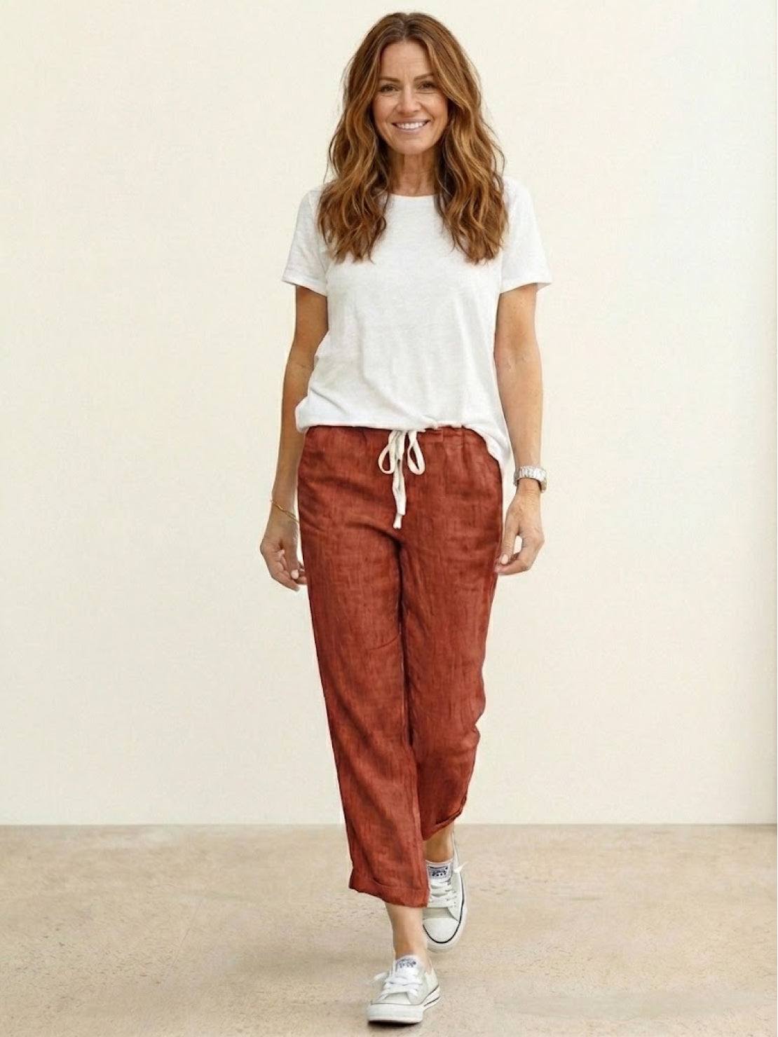 Woman wearing breezy relaxed fit straight pants in orange and black colors standing outdoors