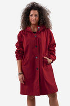 Woman wearing oversized red Rain Couture Windbreaker jacket, lightweight and water-resistant with buttons and hood.