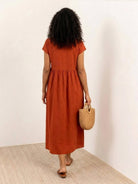 Woman wearing capped-sleeve voluminous pleated midi dress with pockets and flowing silhouette