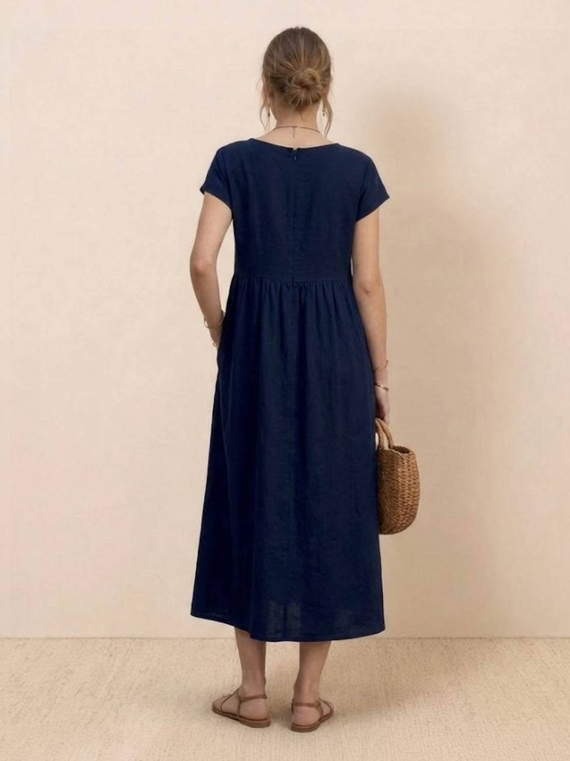 Woman wearing capped-sleeve voluminous pleated midi dress with pockets and a flowing silhouette