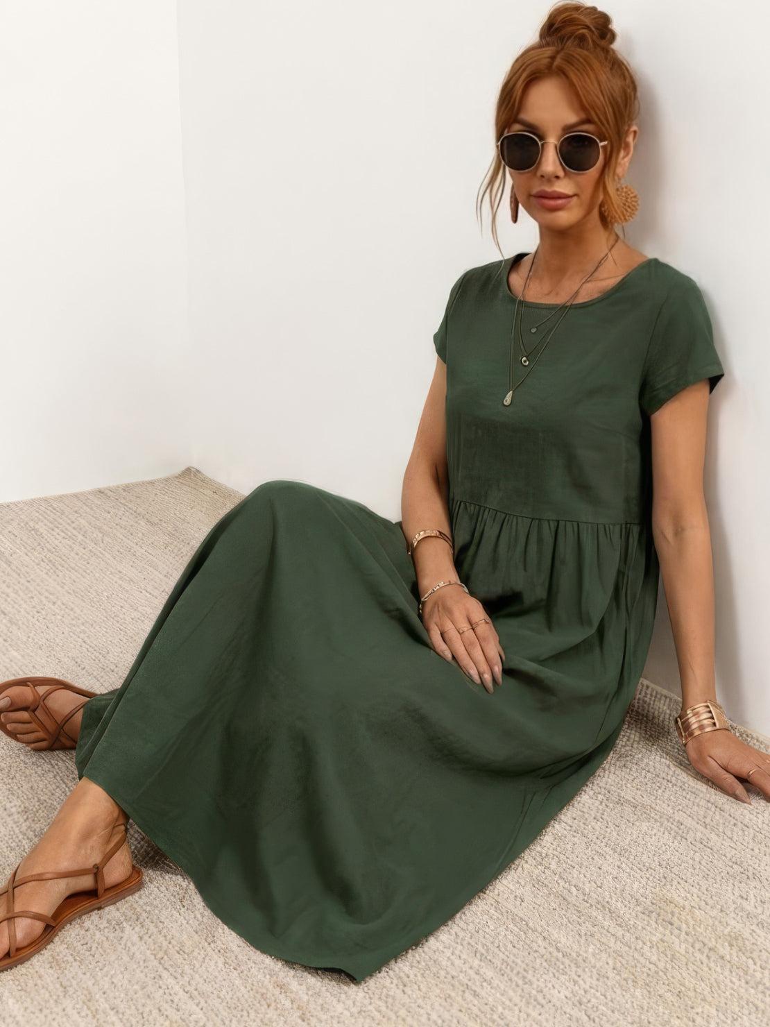 Woman wearing a capped-sleeve voluminous pleated midi dress with a flowing skirt and pockets